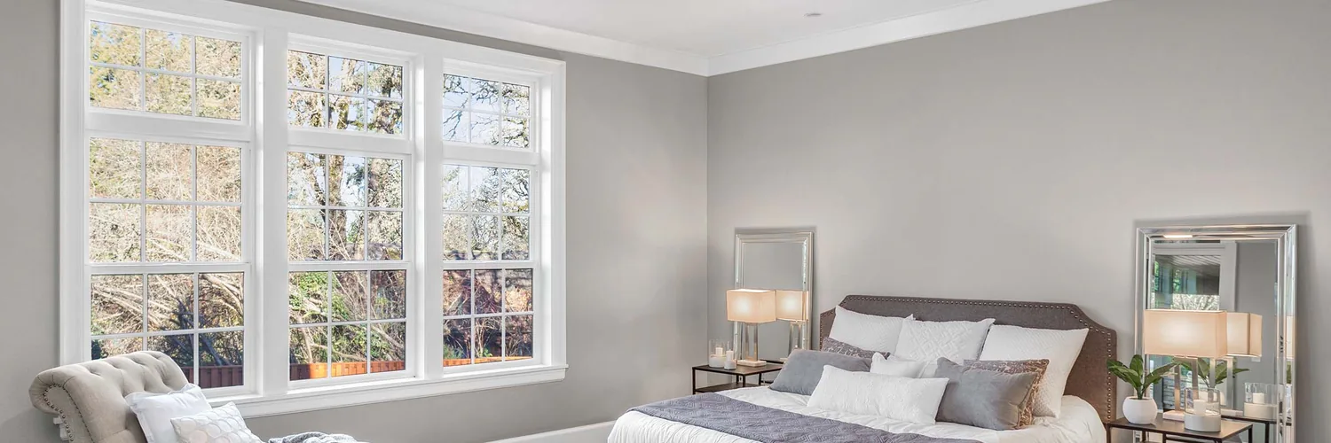Climate Solutions 8100 Series white double-hung windows with optional grids in a bedroom installation